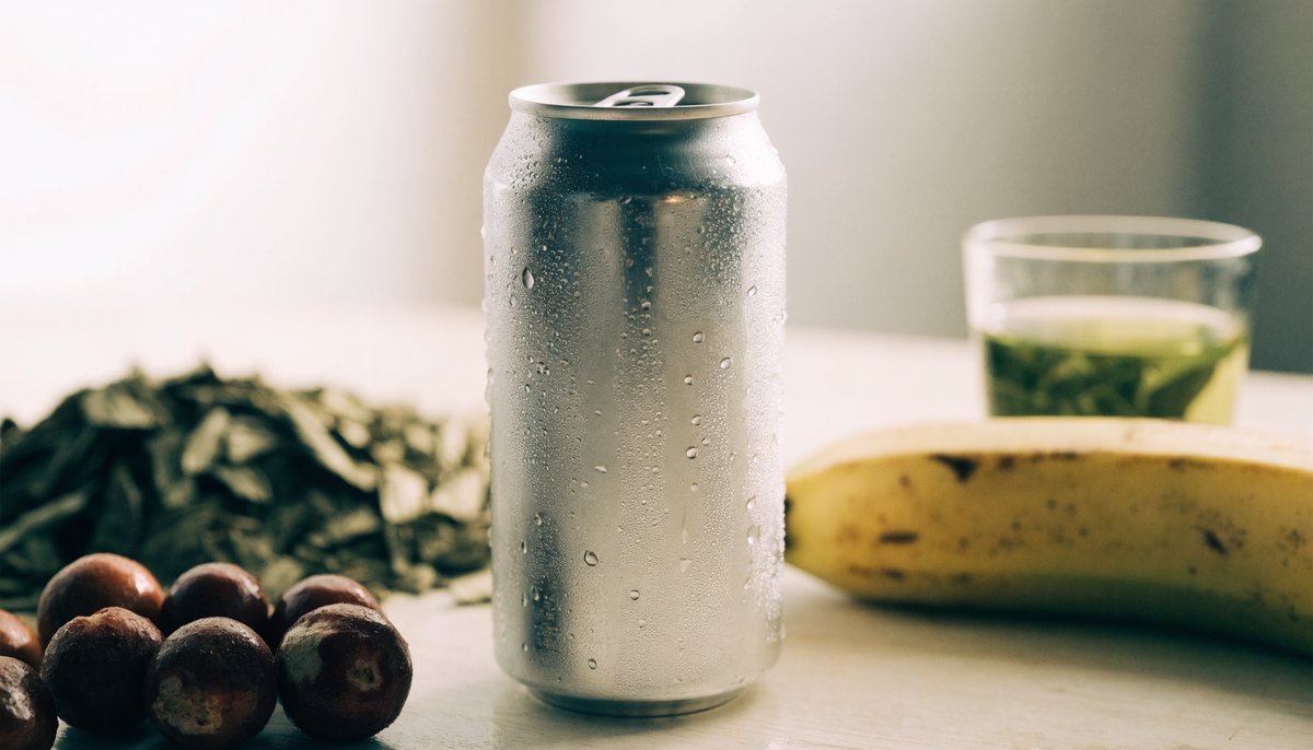 Canette de boisson énergisante naturelle entourée de guarana, yerba maté, banane et thé vert sur du bois clair