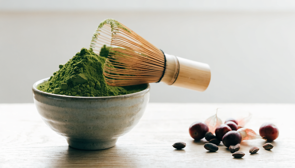 Poudre de matcha et graines de guarana sur une table en bois clair