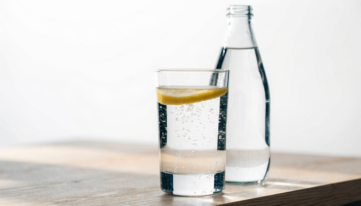 Grand verre d'eau pétillante avec une rondelle de citron et des cristaux de sel minéral